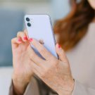 Older person with painted nails holds a mobile phone